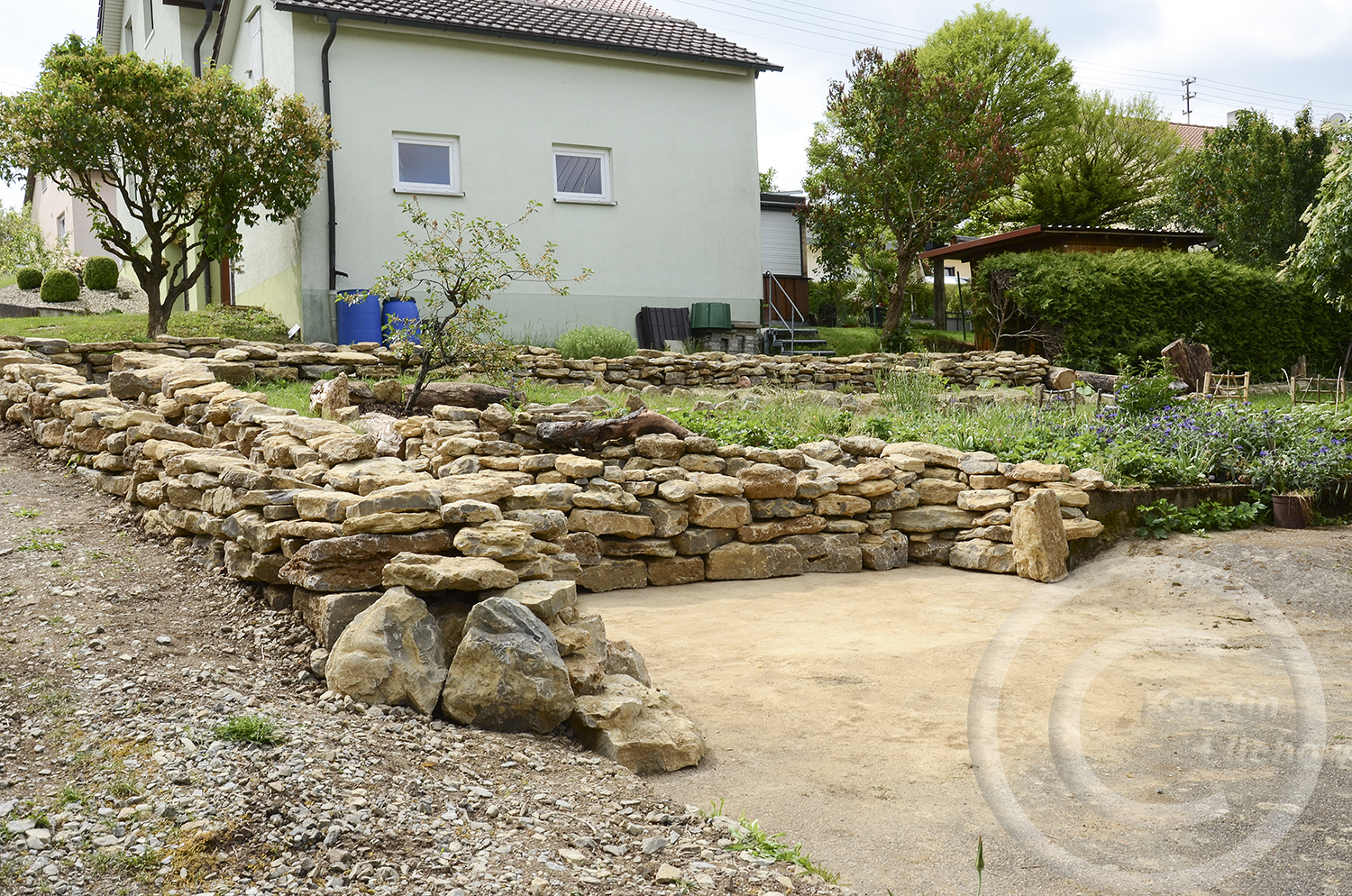 Geschafft. Die Mauer steht. Aber es sind immer noch Steine übrig. Deshalb wird im Gemüsegarten weitergebaut, die Reststeine dienen dort als Beetbegrenzung.