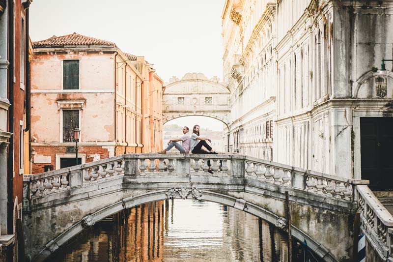 LGBTQ+ couple enjoys an intimate and romantic moment on a Venice bridge during their photoshoot.