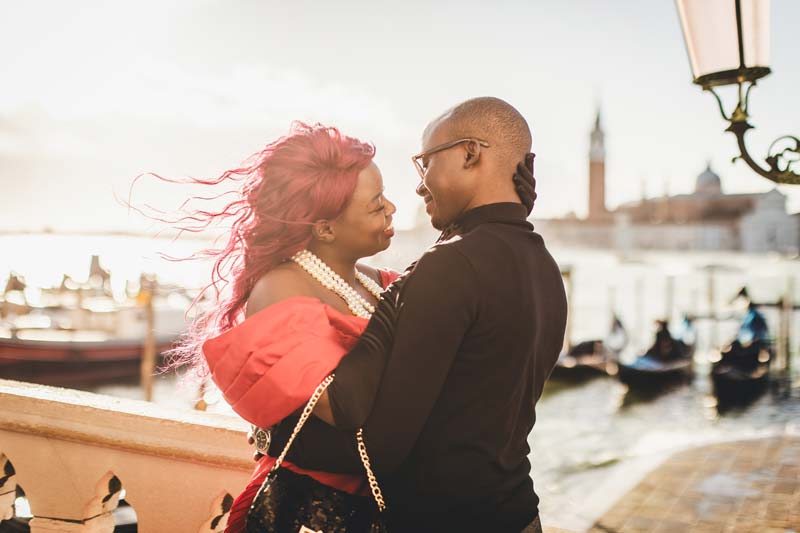 A couple kissing on a traditional bridge in venice