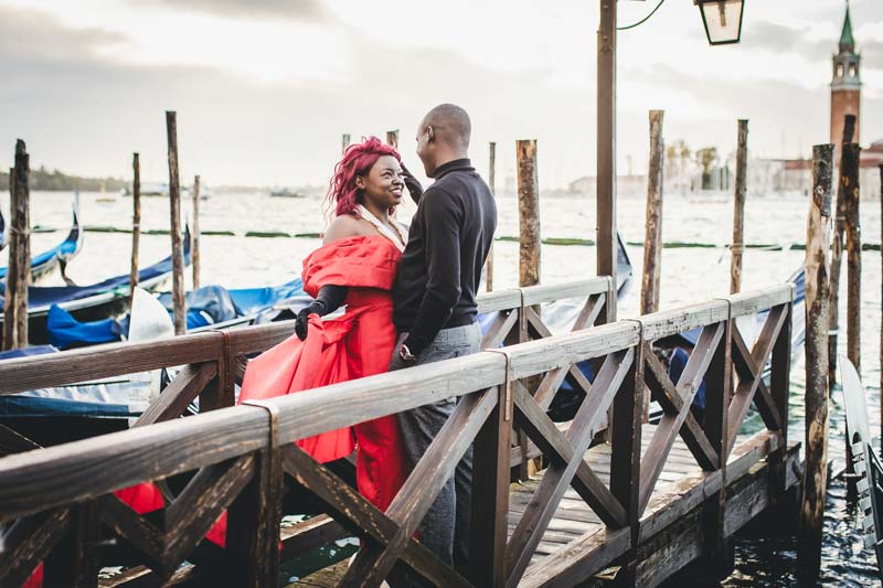 A happy couple in a warm embrace on a bridge overlooking the Grand Canal during their Venice anniversary photoshoot.