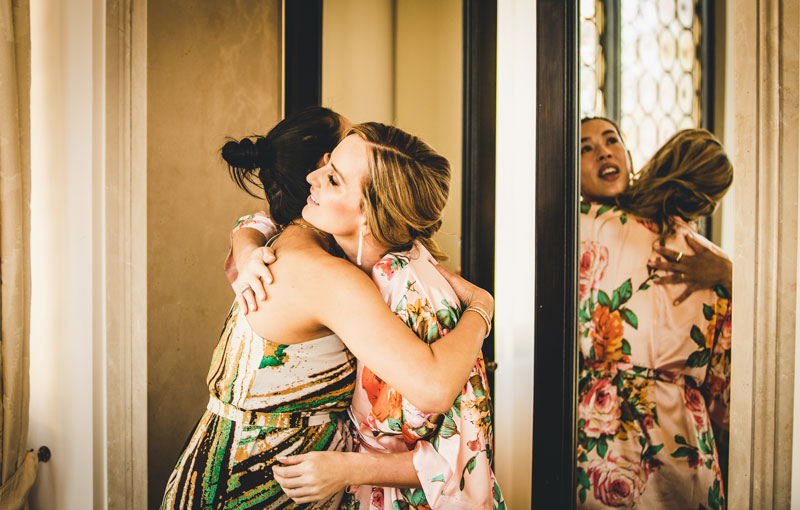The bride smiles as she gets ready, with the elegant decor of the Ca' Nigra Hotel in the background.