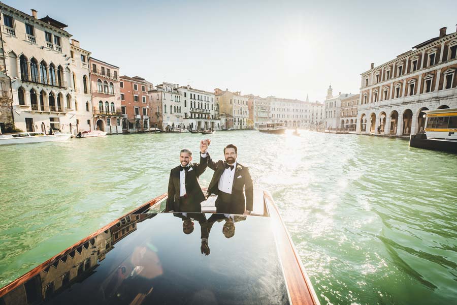 An LGBTQ+ couple celebrating their love in a historic Venetian water taxi.