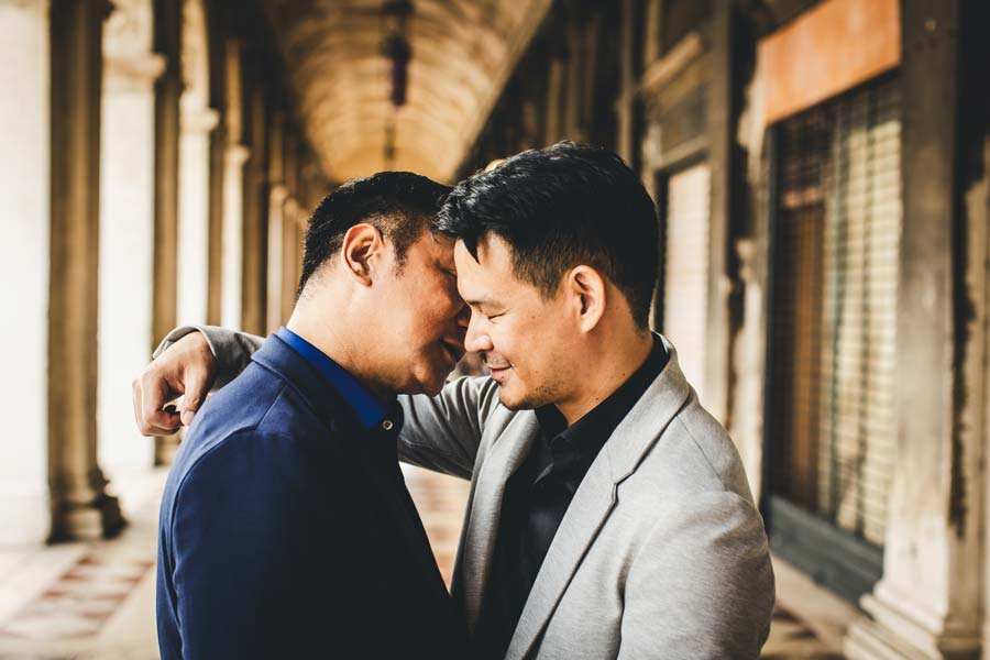 Gay couple holding hands in front of Basilica di San Marco during golden hour