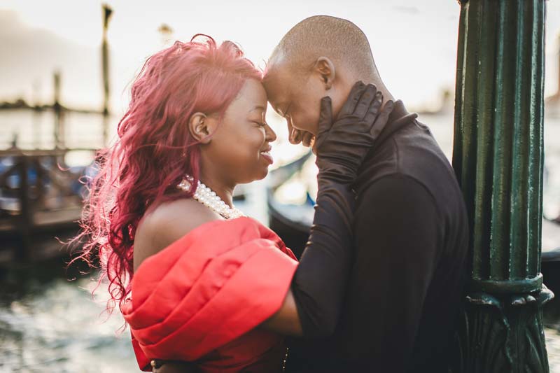 A close-up of a smiling couple celebrating their anniversary with a toast and a backdrop of Venetian architecture.