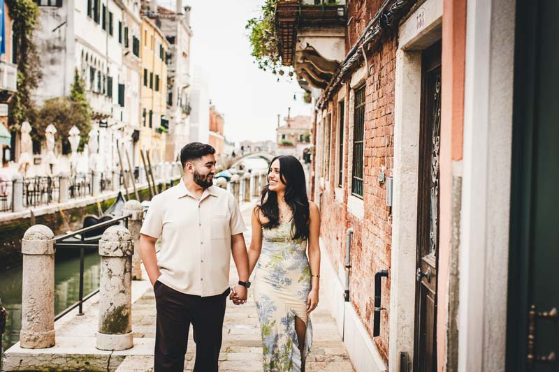 Candid photo of a happy couple walking through a narrow Venetian alley.