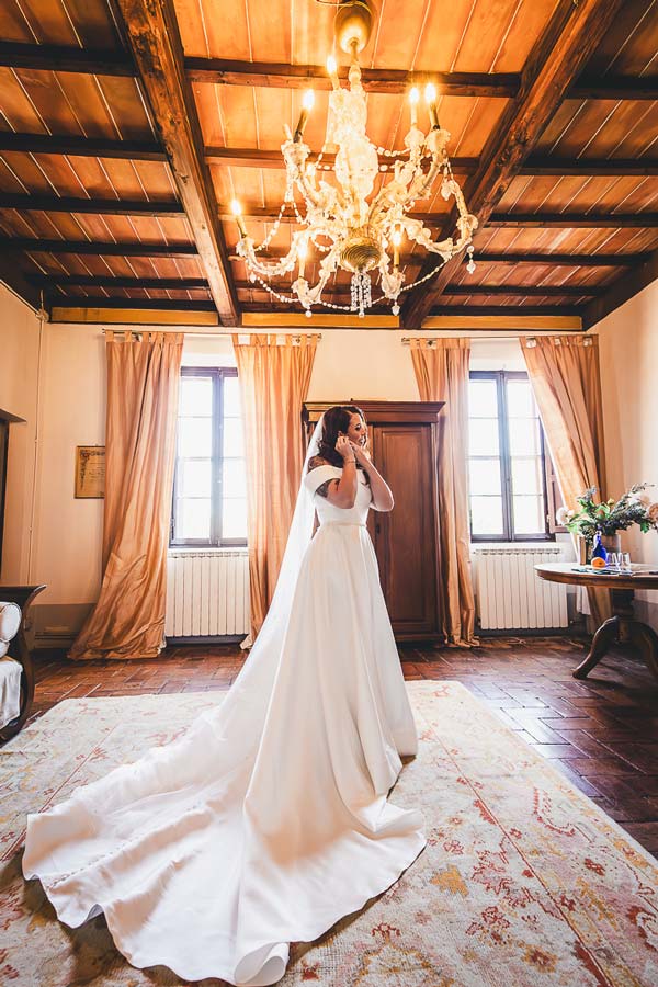 Wedding photographer Tuscany capturing two brides walking together in a historic Italian castle garden