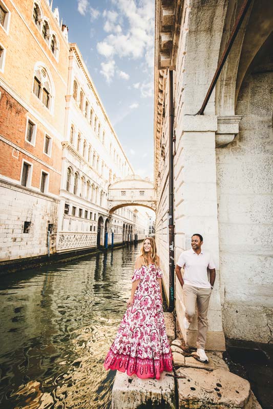 Three sisters holding hands on a small bridge in Venice early morning
