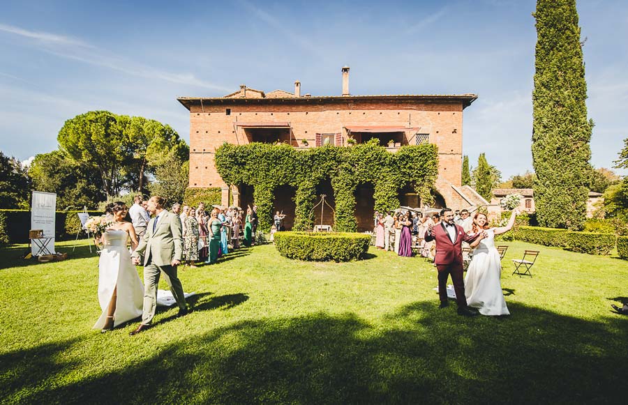 Group photo of two couples and guests at a Tuscany wedding venue surrounded by nature