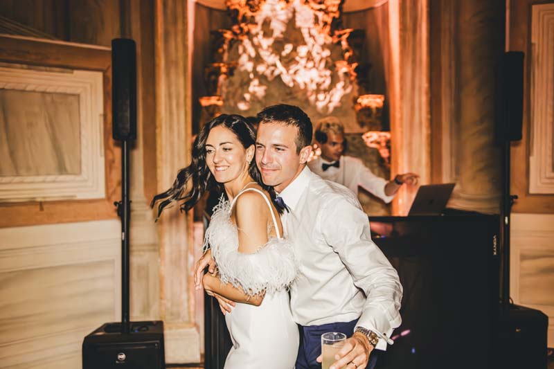 The couple cutting the wedding cake, illuminated by warm light.