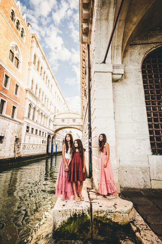 family walking together along a quiet Venetian canal at sunrise
