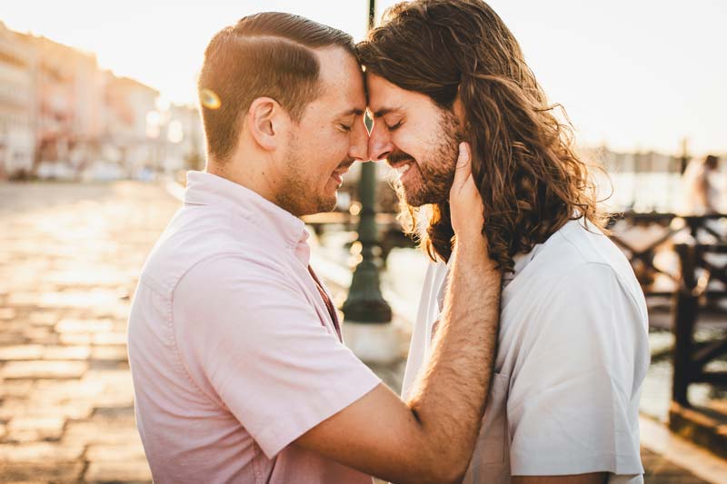 Happy couple during an LGBTQ+ engagement photoshoot in Venice, with radiant smiles.