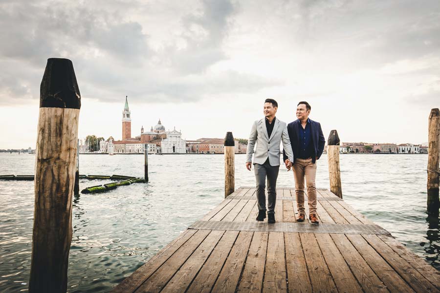 Gay couple walking along the Grand Canal in Venice at dawn