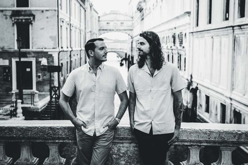 Black and white image of an LGBTQ+ couple laughing during their Venice photoshoot.