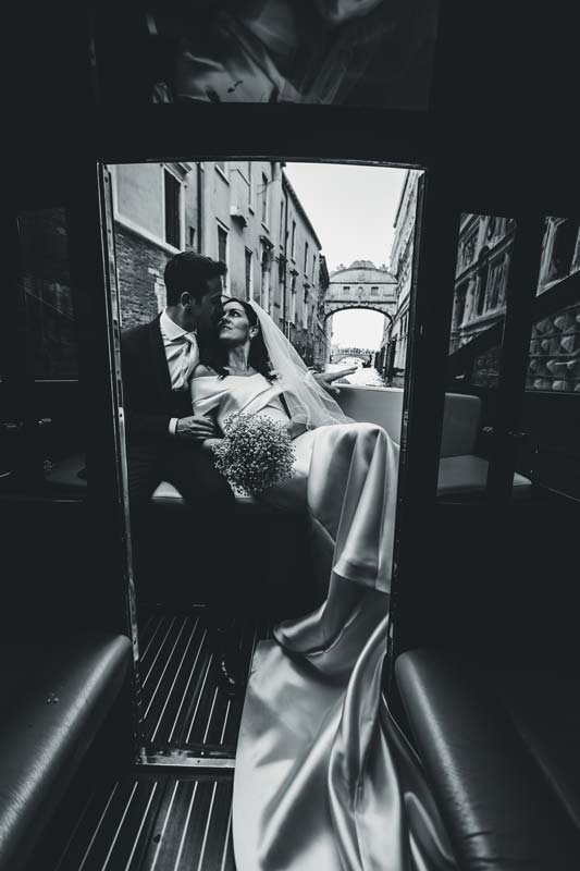 Bride and groom embracing near the Rialto Bridge at sunset.