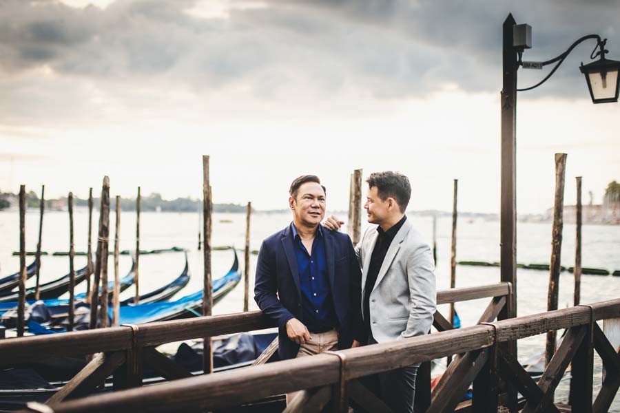 Portrait of a gay couple by the gondolas at sunrise
