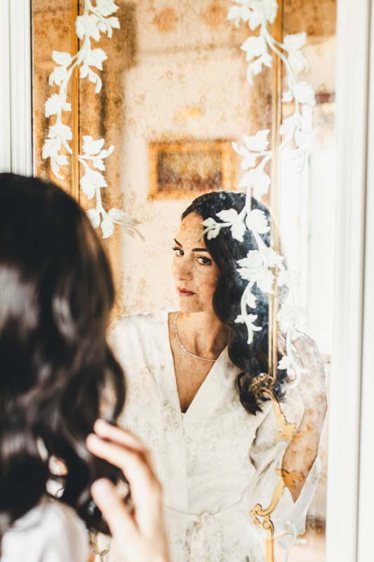 Elegant shot of the bridal gown hanging near a Venetian window.