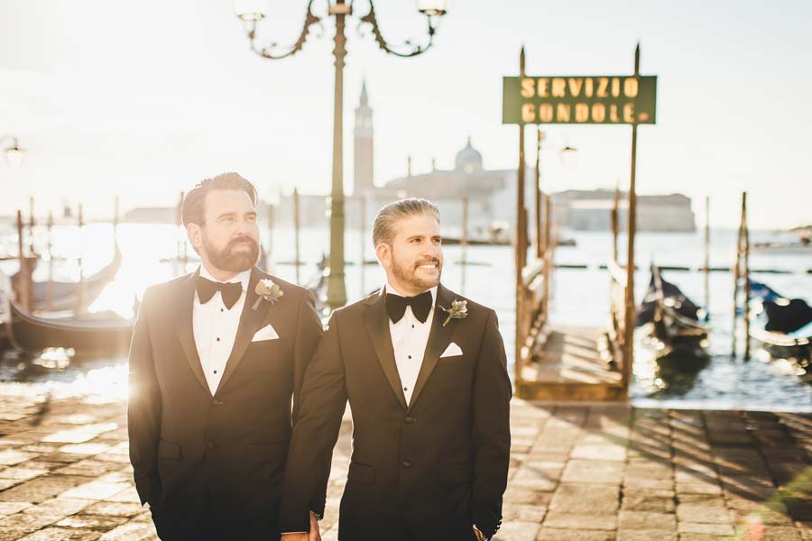 Gay couple walking in St. Mark’s Square at sunrise during their Venice elopement.