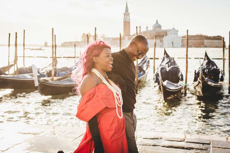 A couple holding hands while walking through a quiet, romantic Venetian alley.