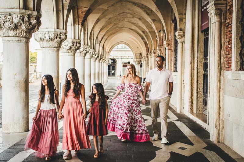 Parents holding hands with their children along the Venetian waterfront