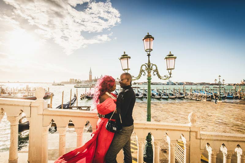 A couple walking under the arches of the Doge's Palace during a romantic walk for their photoshoot.