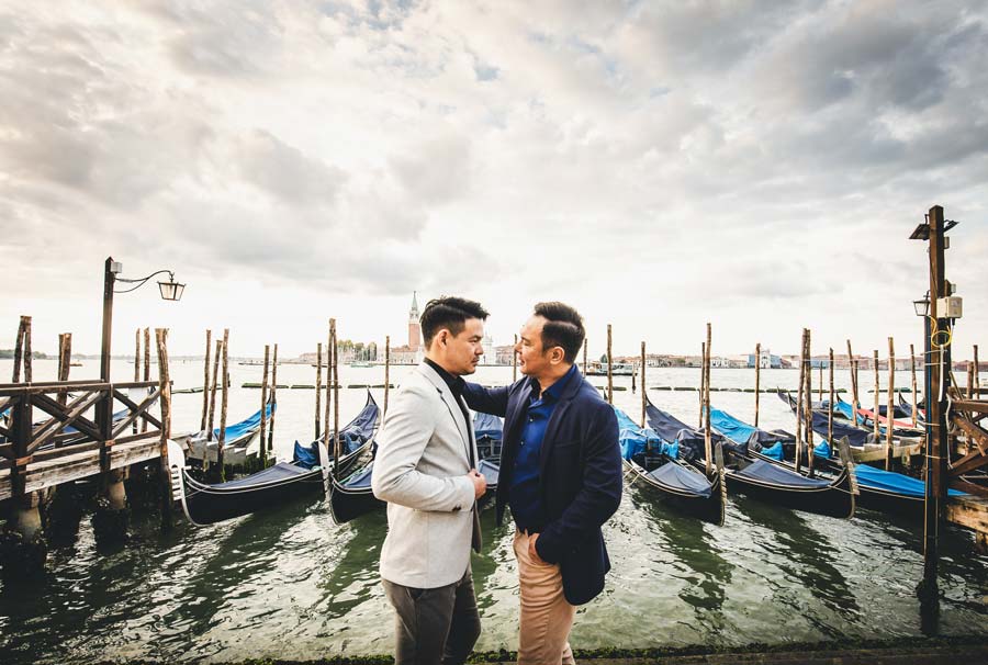 Engaged gay couple sharing a candid moment in Venice at sunrise