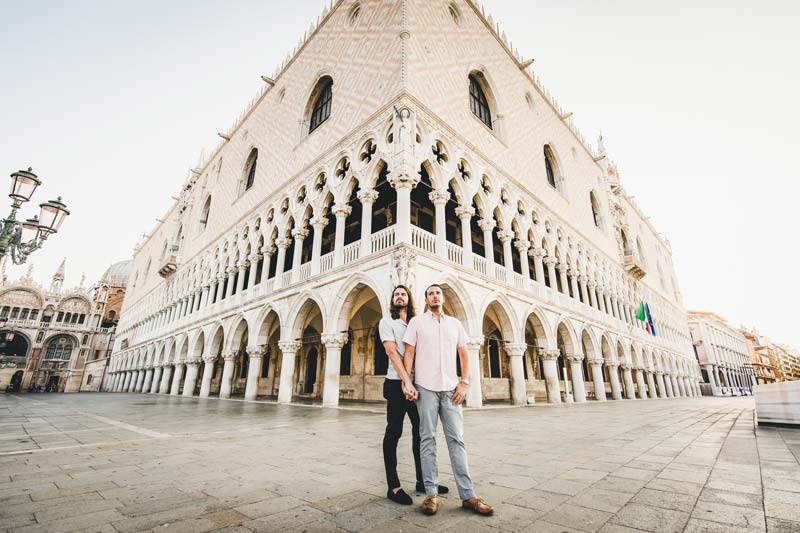 Gay couple photoshoot in Venice at sunrise, with warm colors reflecting on the canal water.