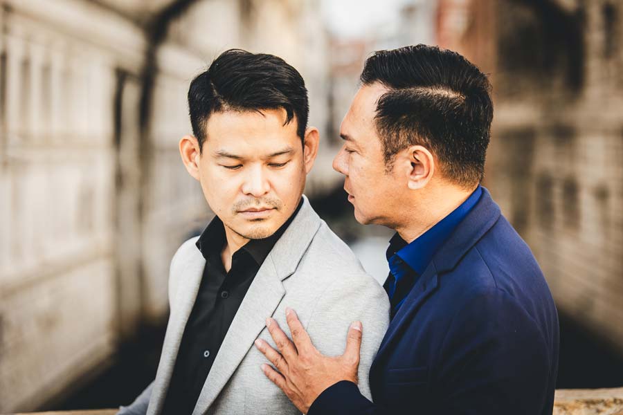Gay couple kissing on a quiet street in Venice at dawn