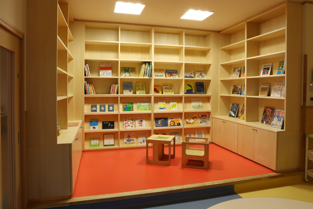 ”ランチルームの図書コーナー”　早番・遅番用に遊具もあります。