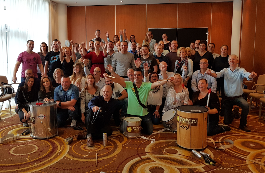 Grootschalige percussie workshop op locatie met authentieke instrumenten en lachende deelnemers.