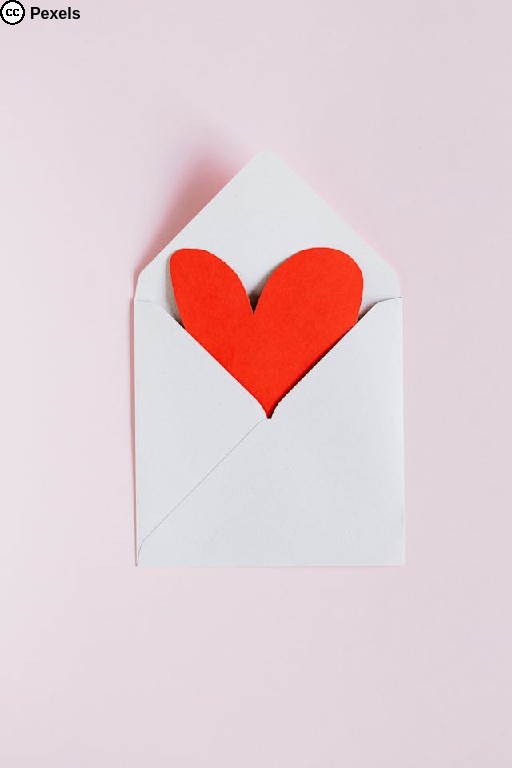 Ein weißer Briefumschlag, in dem ein rotes Herz aus Papier steckt. Foto von Photo By Kaboompics.com auf Pexels.