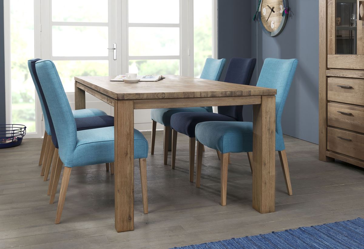 Massiver Holztisch mit sechs gepolsterten Stühlen in Blau- und Türkistönen im Esszimmer.