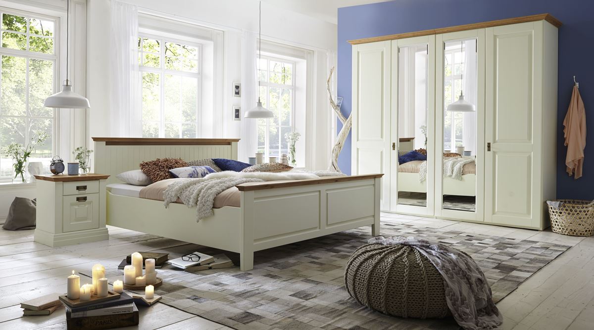 Landhausstil-Schlafzimmer mit cremefarbenem Bett, Spiegelschrank und blauer Akzentwand.