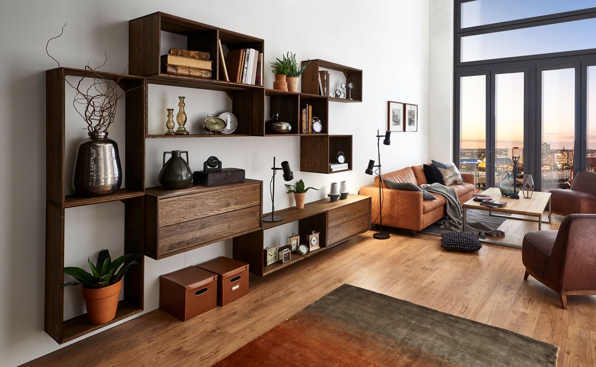 Wohnzimmer mit dunklem Hängeregal, Ledersofa und Fensterfront mit Blick auf die Stadt.