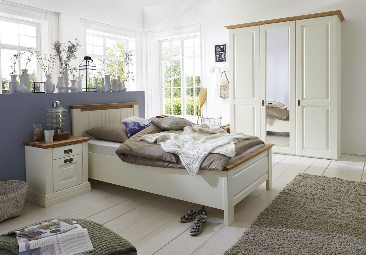 Landhausstil-Bett mit hellgrauer Akzentwand, cremefarbenen Möbeln und hellem Holzboden.