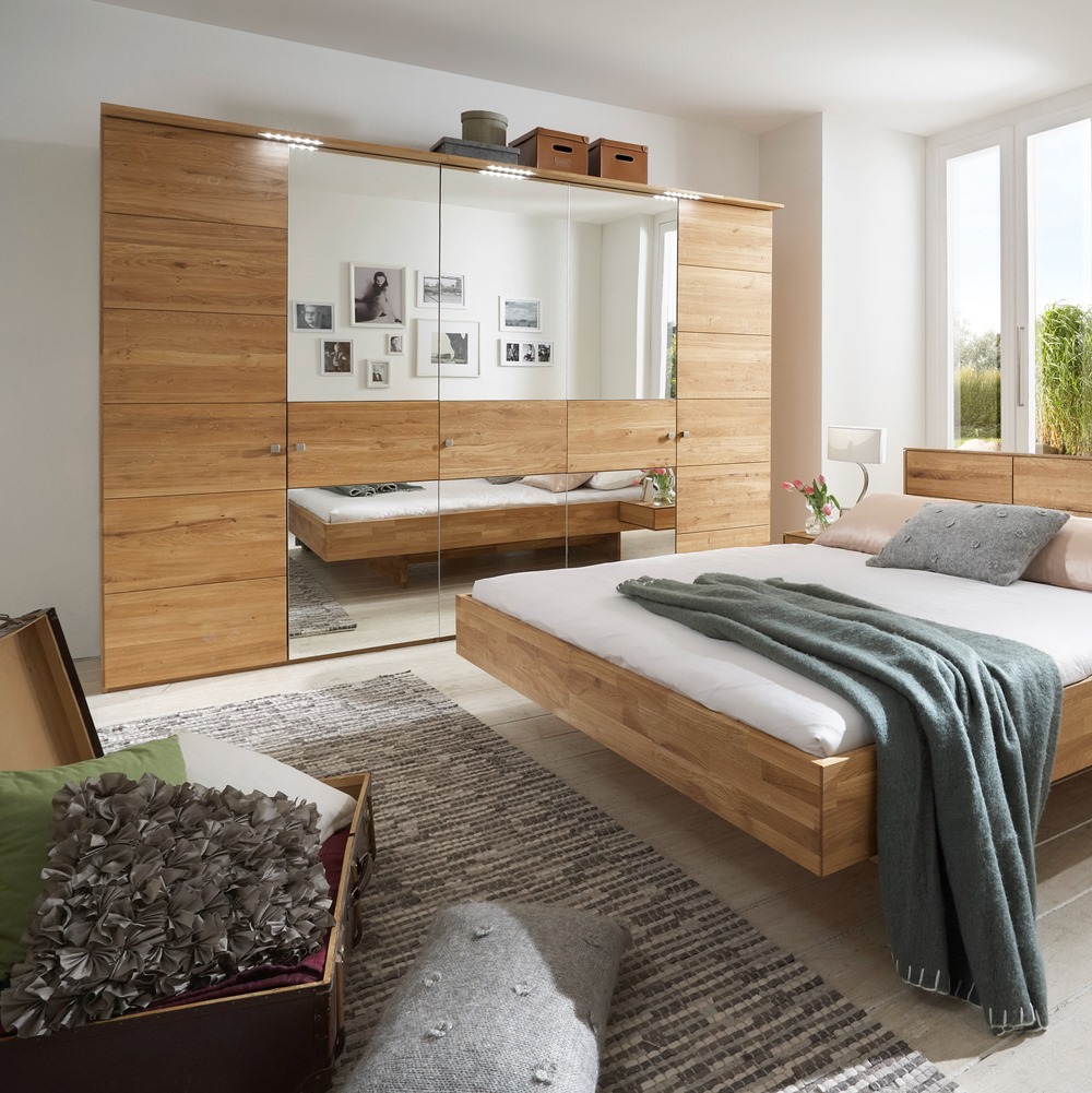 Modernes Schlafzimmer mit Holzbett, großem Spiegelschrank und hellem Licht im Raum.
