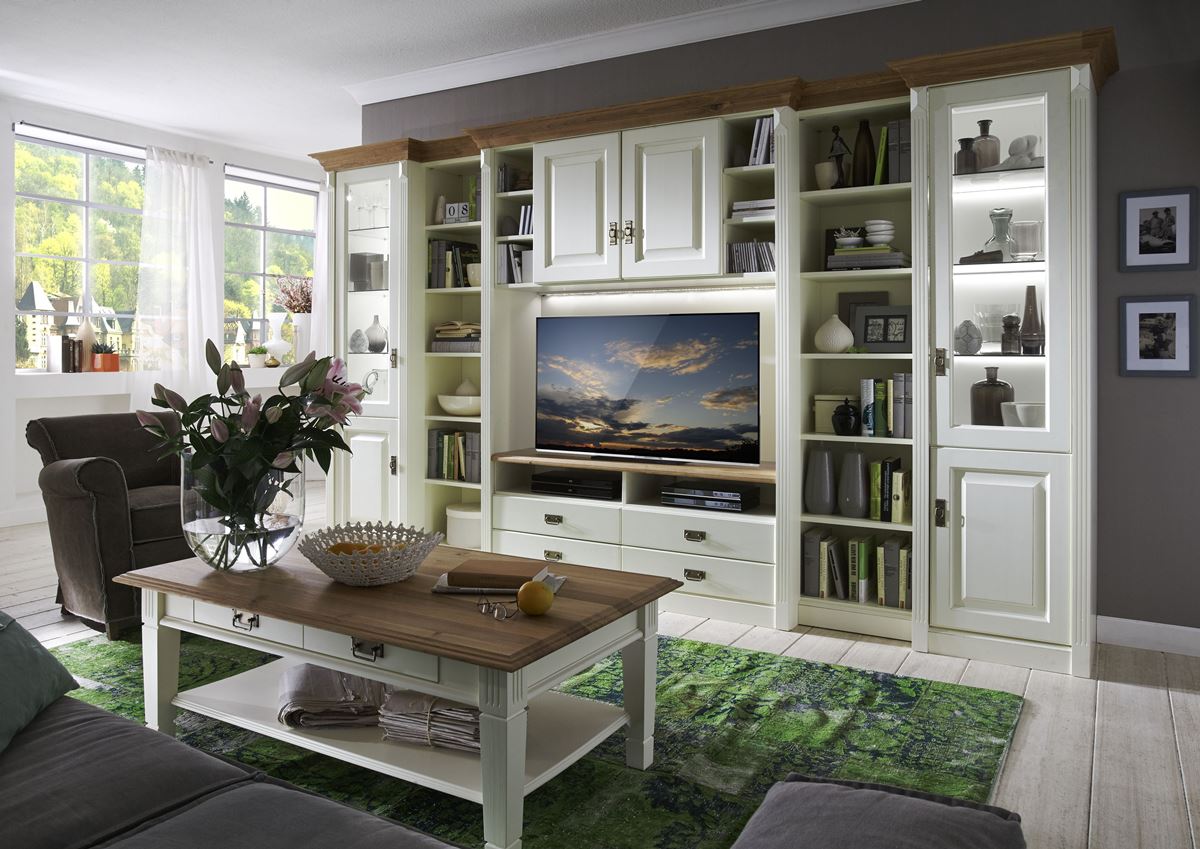 Große weiße Wohnwand im Landhausstil mit TV-Fach, Büchern und einem Couchtisch auf grünem Teppich.