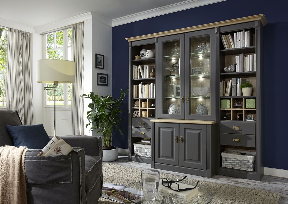 Dunkelgraues Wohnregal im Landhausstil mit Vitrinen, Büchern und einem blauen Wandhintergrund.