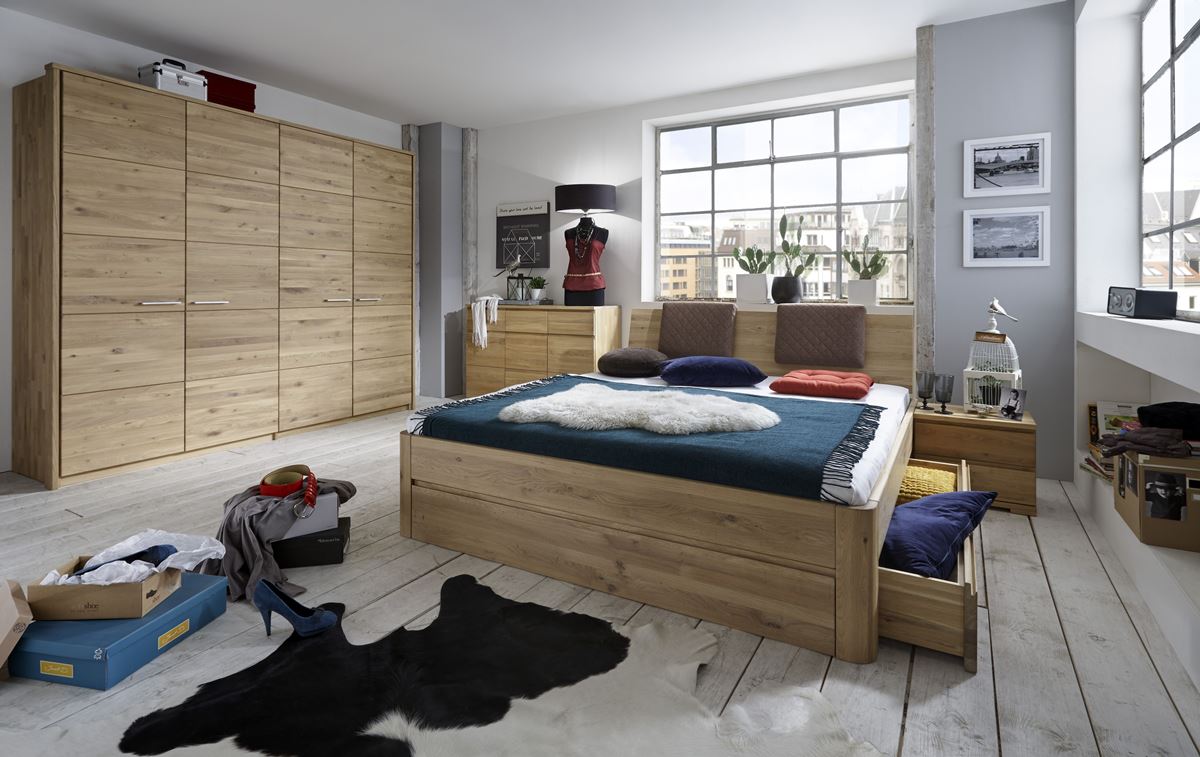 Schlafzimmer mit Holzbett, großem Schrank, hellem Boden und industriellem Fenster.