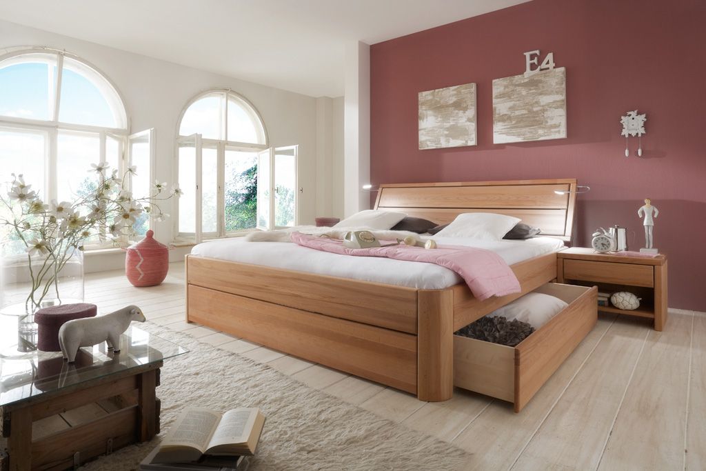Großes Holzbett mit Stauraumschublade in einem rosa Schlafzimmer, mit Bogenfenstern.