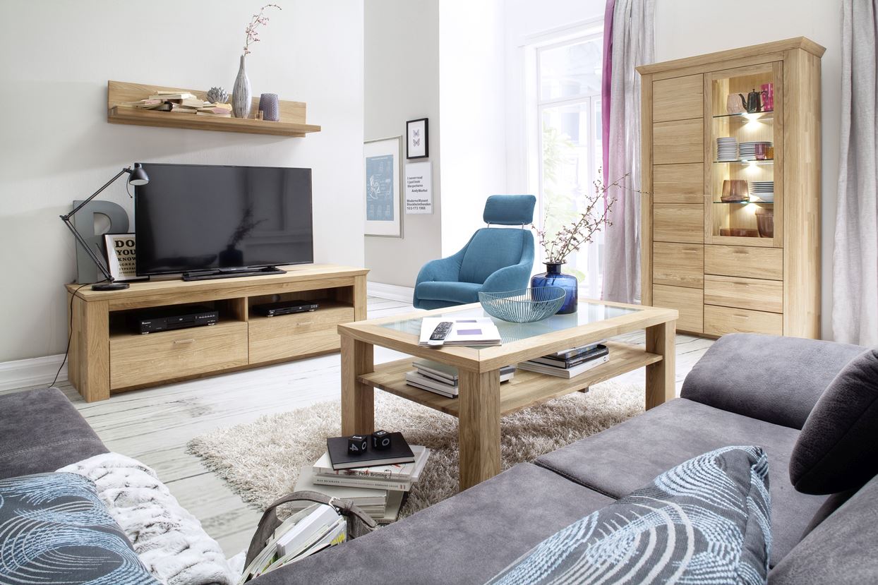 Wohnzimmer mit Massivholzmöbeln, flauschigem Teppich und einem grauen Sofa.