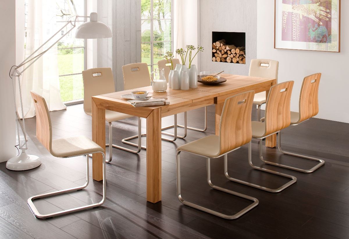 Rechteckiger Holztisch mit acht Freischwinger-Stühlen in hellem Esszimmer mit dunklem Boden.