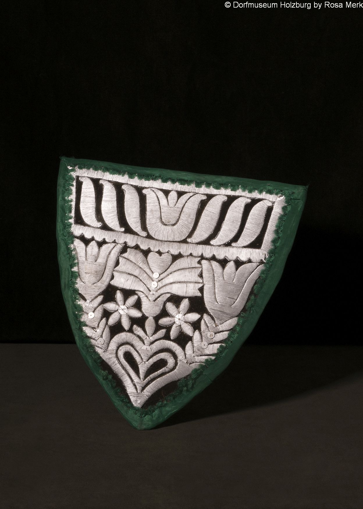 Brustlappen, 19. Jh., mit Silberfäden über Schablone gestickt (Sprengtechnik), mit  grünem Moiréeband eingefasst