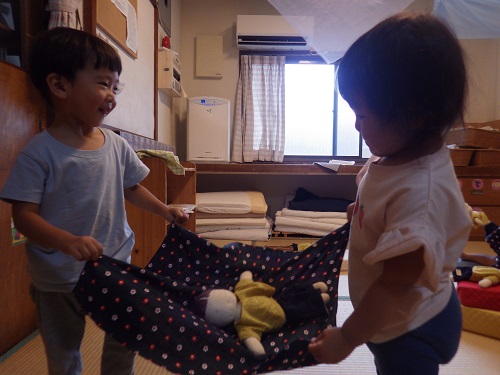 「そっちもって」と友だちを誘ってわらべうたあそび。（1歳児）