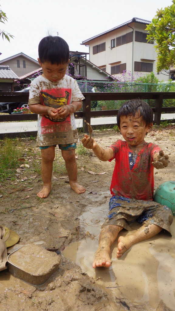 未満児(２歳児)全身どろんこになって大胆にあそぶ子どもたち。水や泥の感触をめいっぱい楽しんでいます。