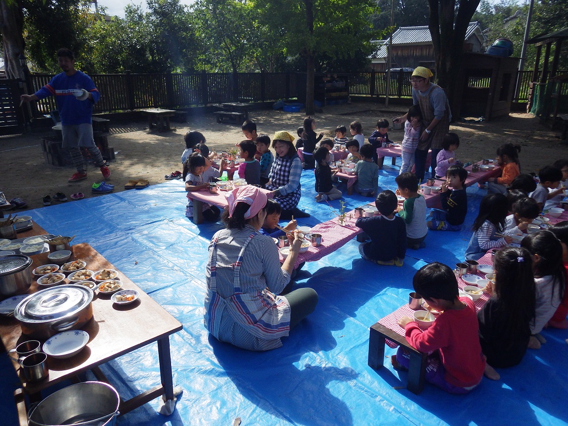 「収穫祭」秋の恵みに感謝して、園で育てて収穫したさつま芋や里芋をいれてやま・そら(４・５歳児) はエプロンをつけてクッキングをしました。園庭にかまどを作って秋空の下、みんなでおいしくいただきました。