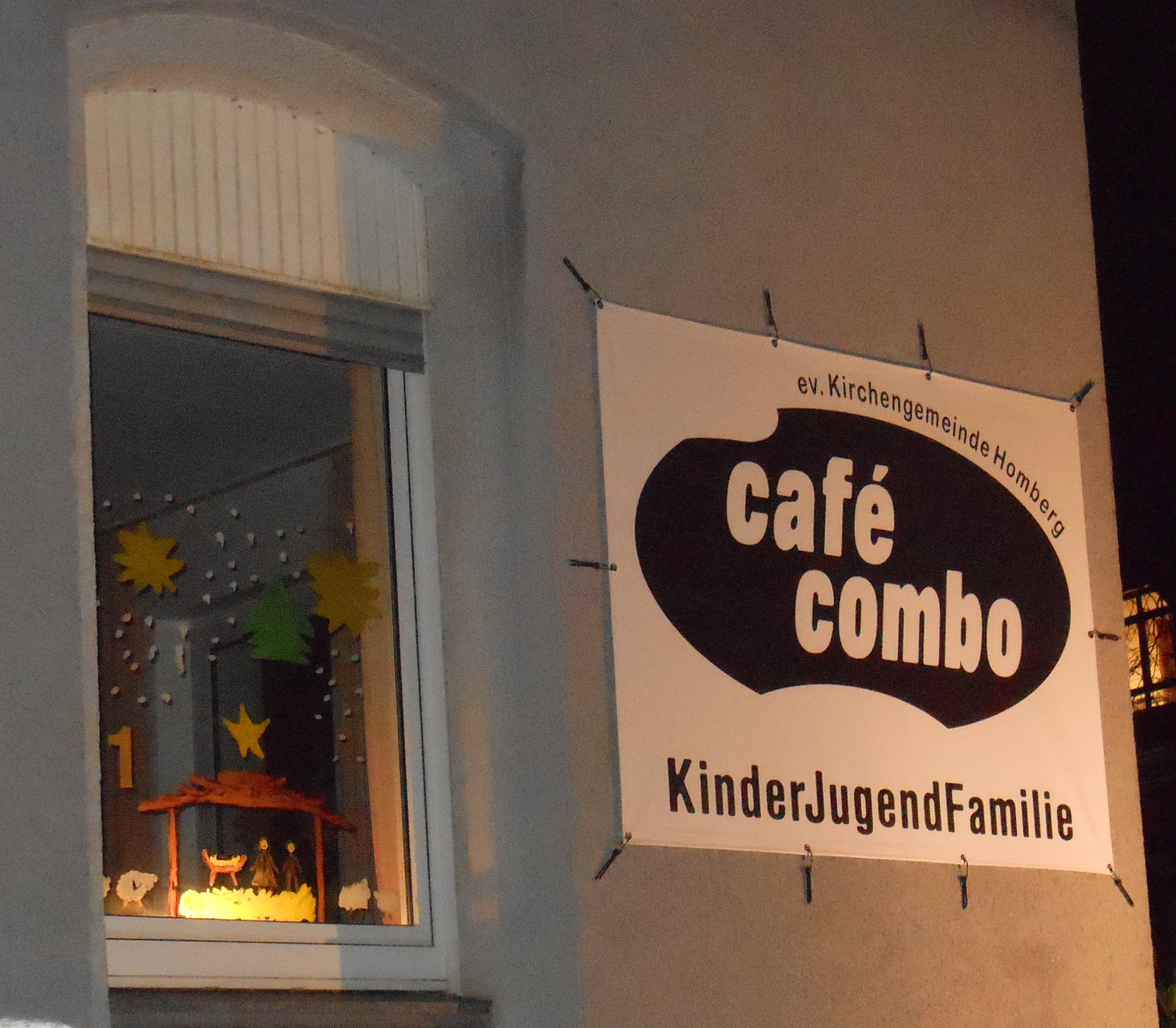 Unter dem "fast neuen" Logoplakat des Café Combo eröffnet die Krabbelgruppe Alt-Homberg den diesjährigen "lebendigen Adventskalender"