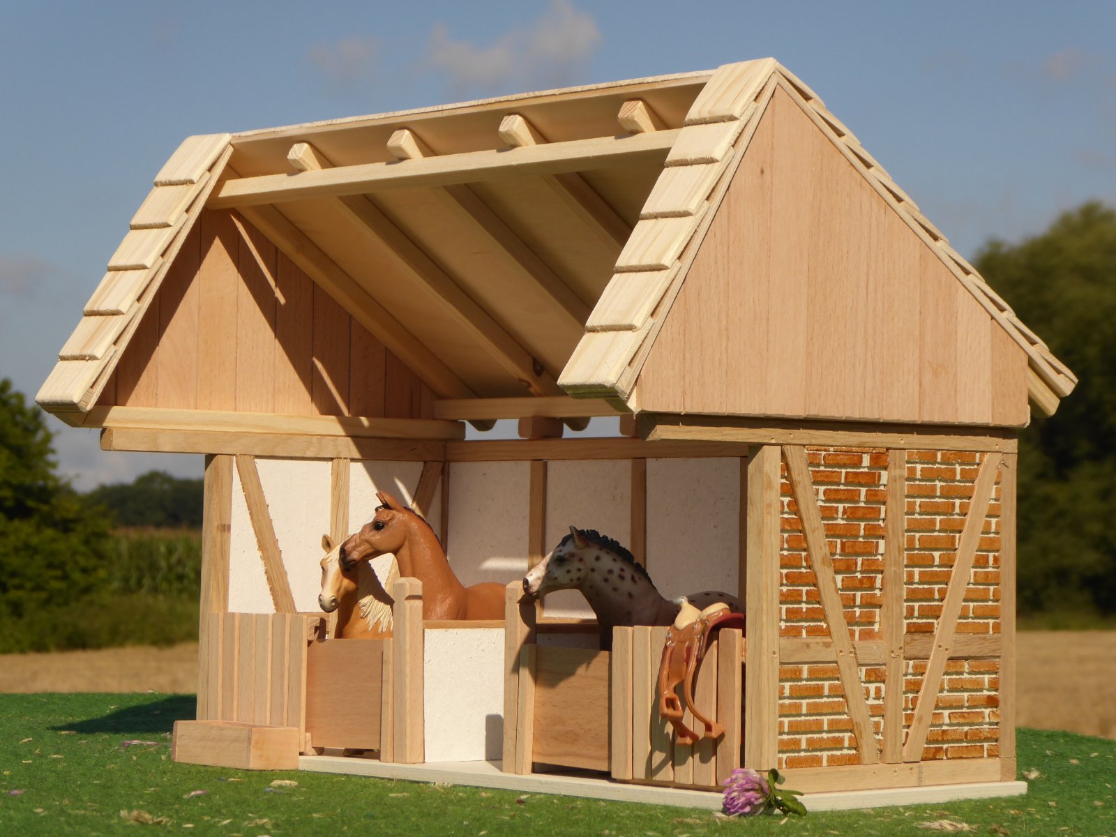 Pferderemise aus Holz mit Pferden in den Boxen