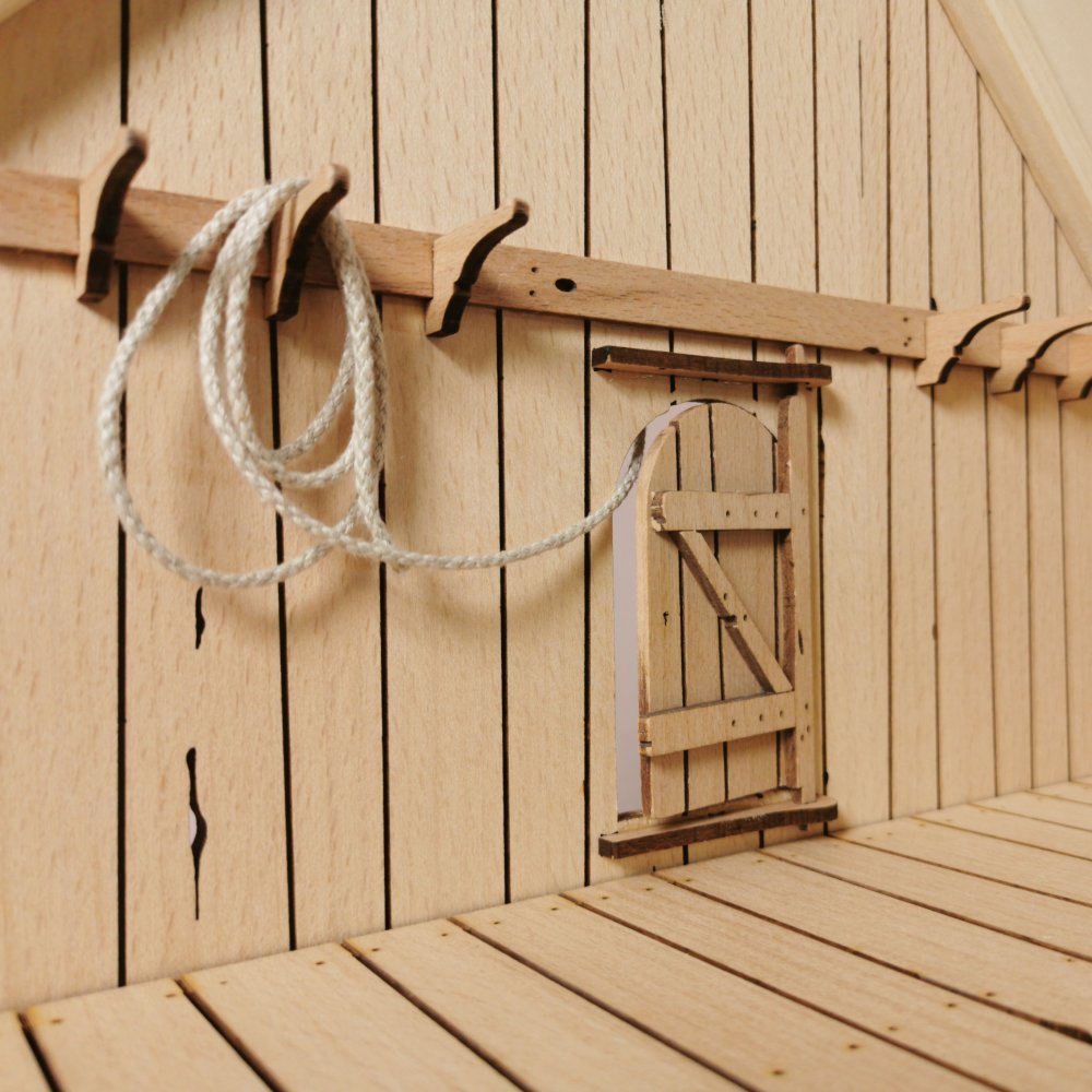 Detail der Stallinnenwand mit Halfter, Zaumzeug und Hakenregal