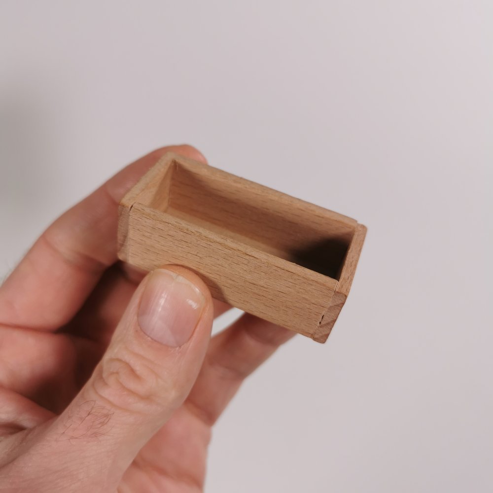 Futtertrog aus Holz in der Hand