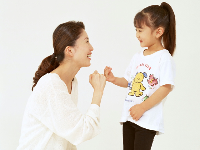 お母さんと女の子が笑って指切りをしている画像